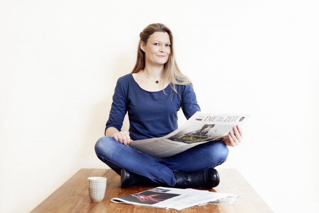 Eine Person sitzt mit einer Zeitung auf einem Tisch