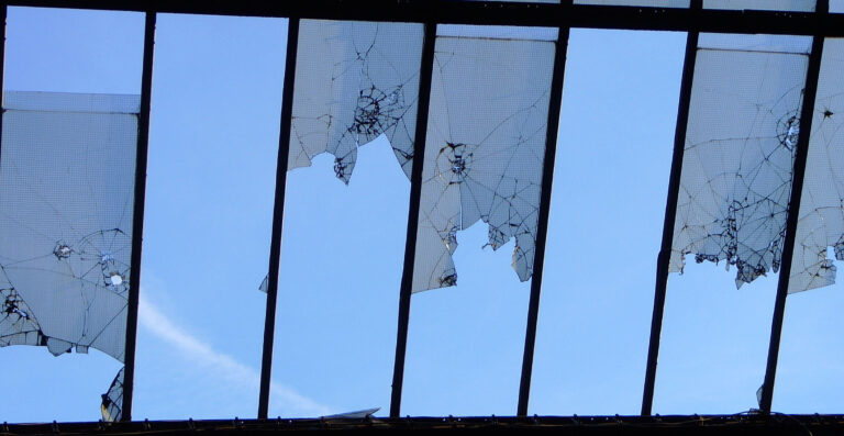 Blick durch ein Fenster mit zerbrochenen Scheiben